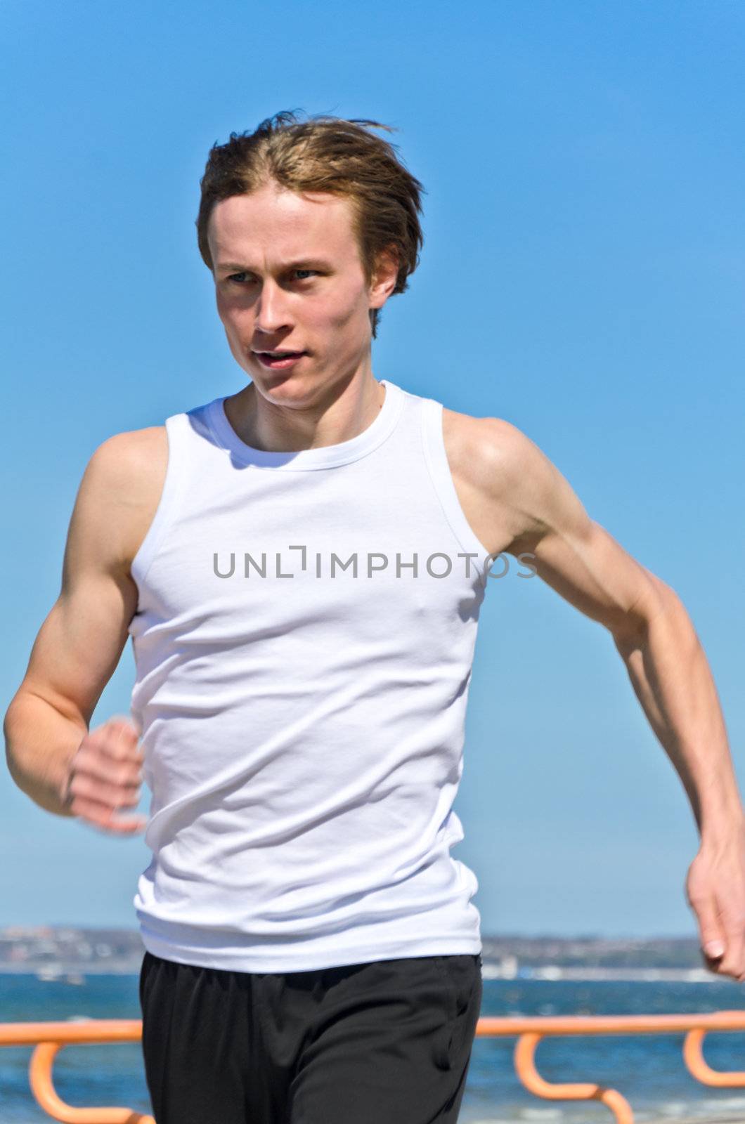 Athletic young male running on the shoreline