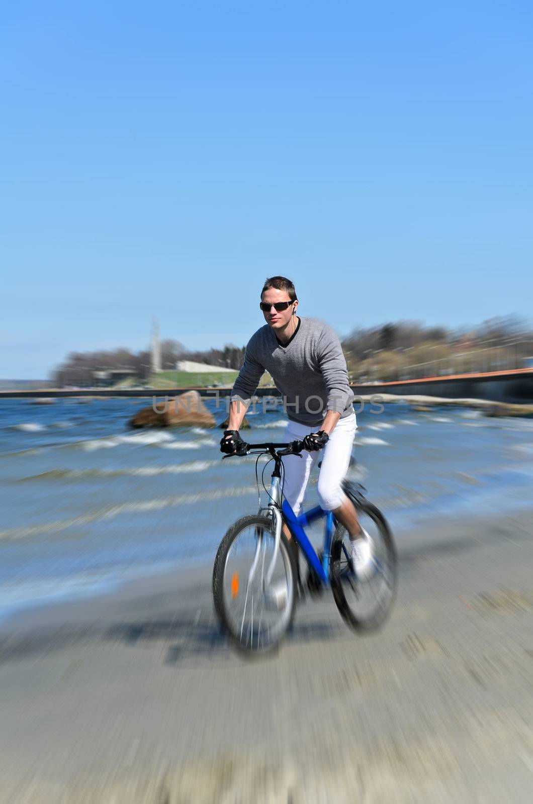 Motion blur: male riding a bicycle by the sea