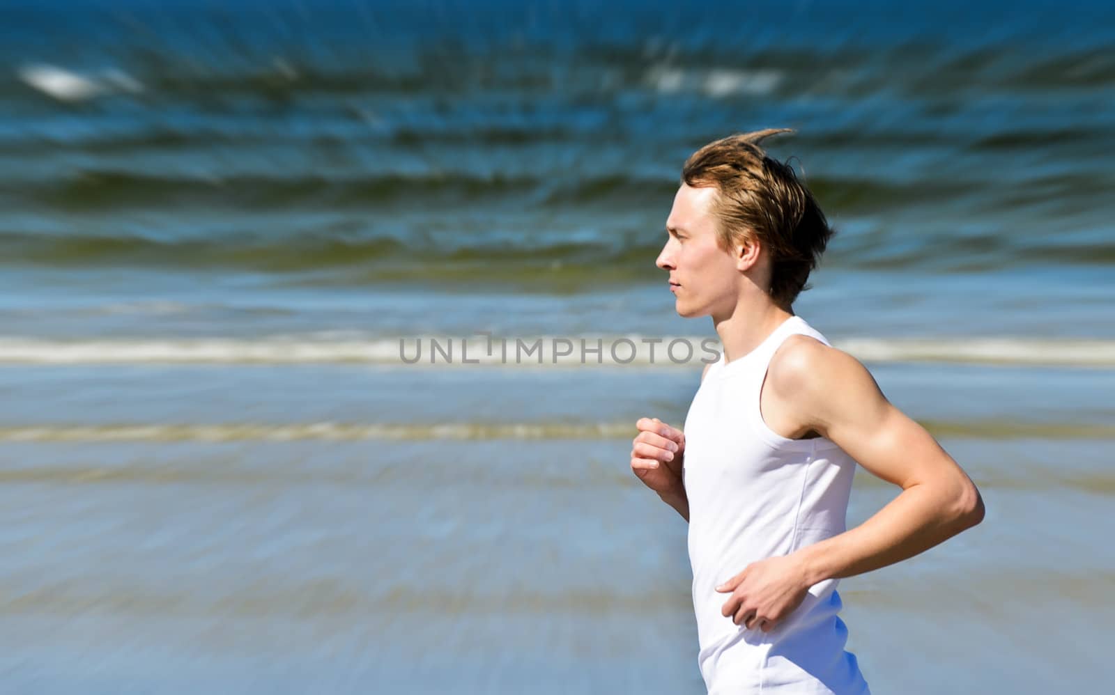 Motion blur: Athletic young male running on the beach