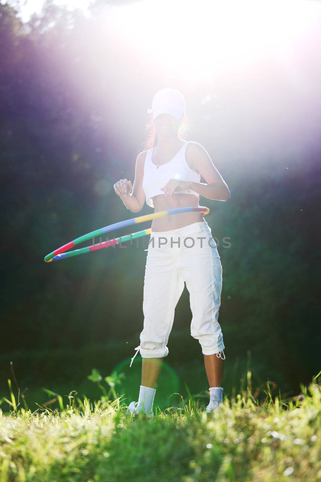 woman rotates hula hoop on nature background