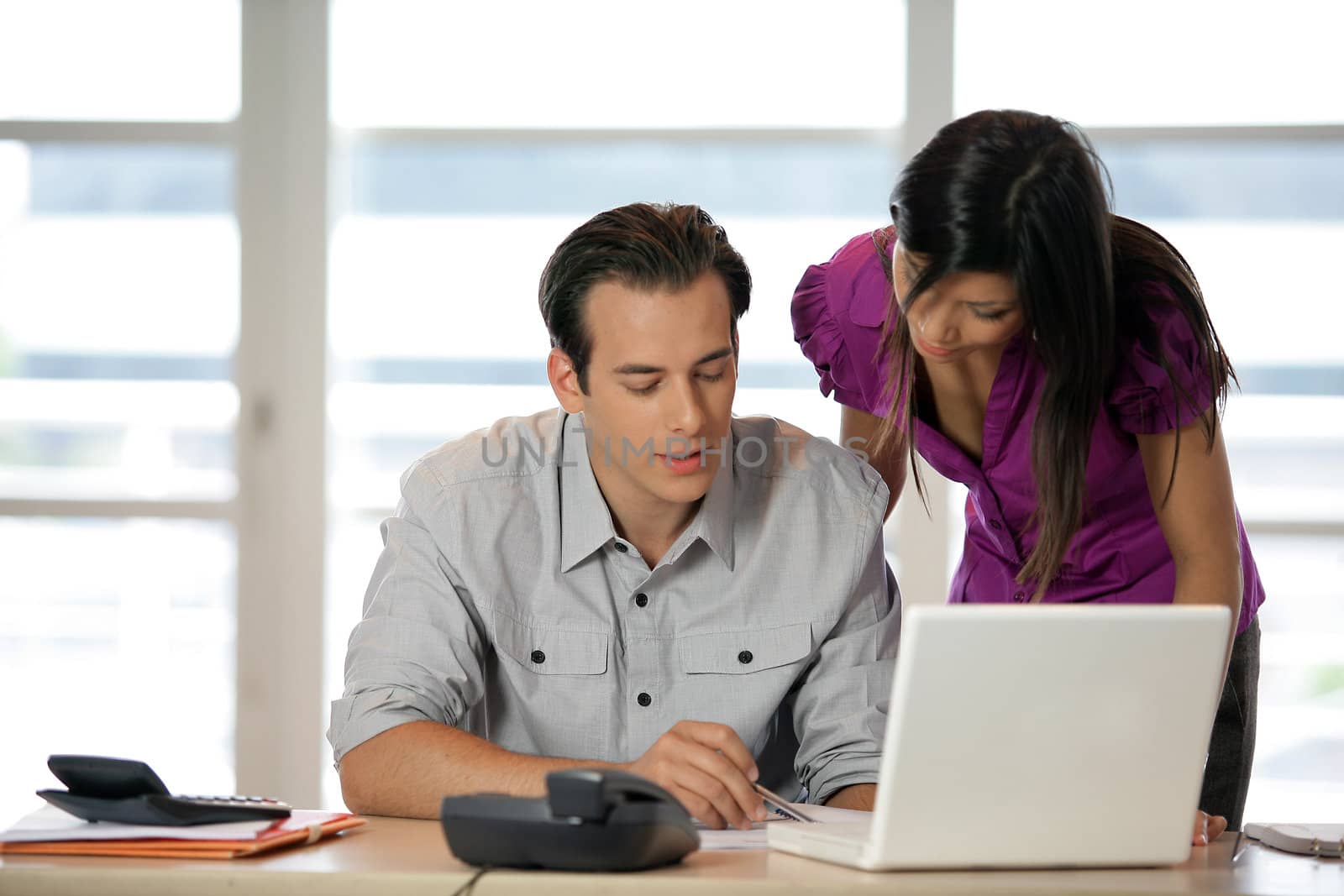 Couple at a desk with a laptop by phovoir