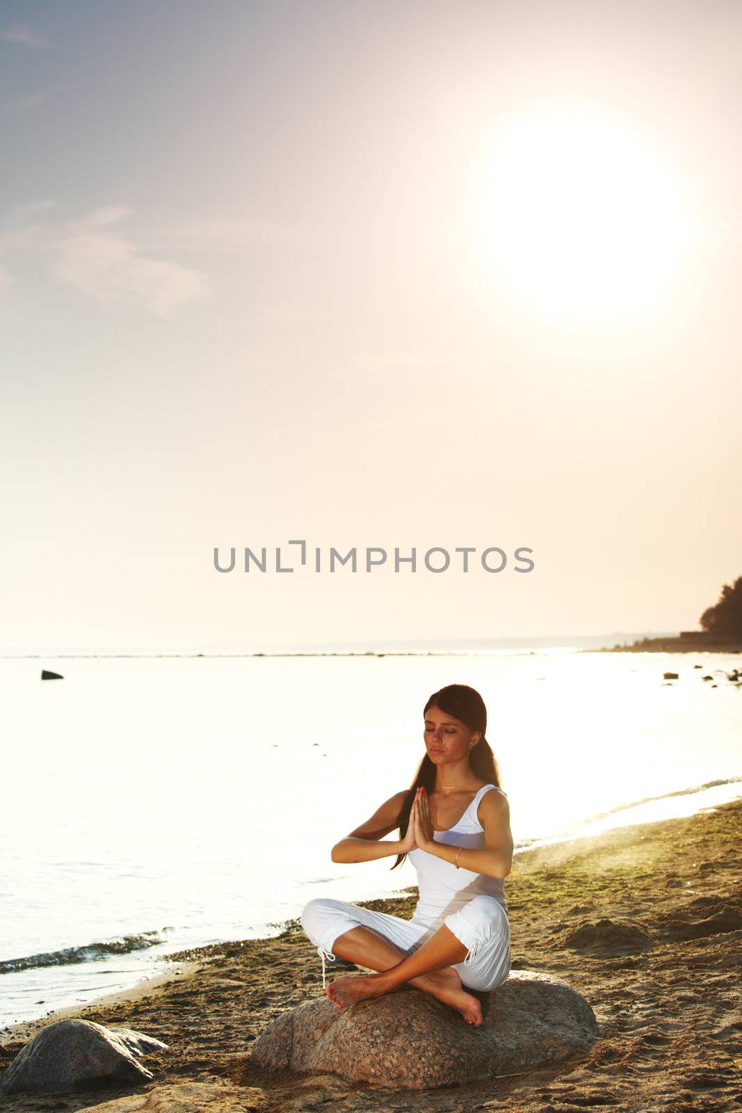 Young woman practicing yoga  near the ocean