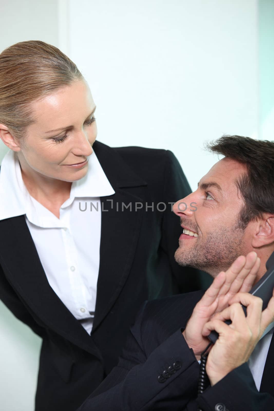 Businessman and woman looking into each other's eyes by phovoir