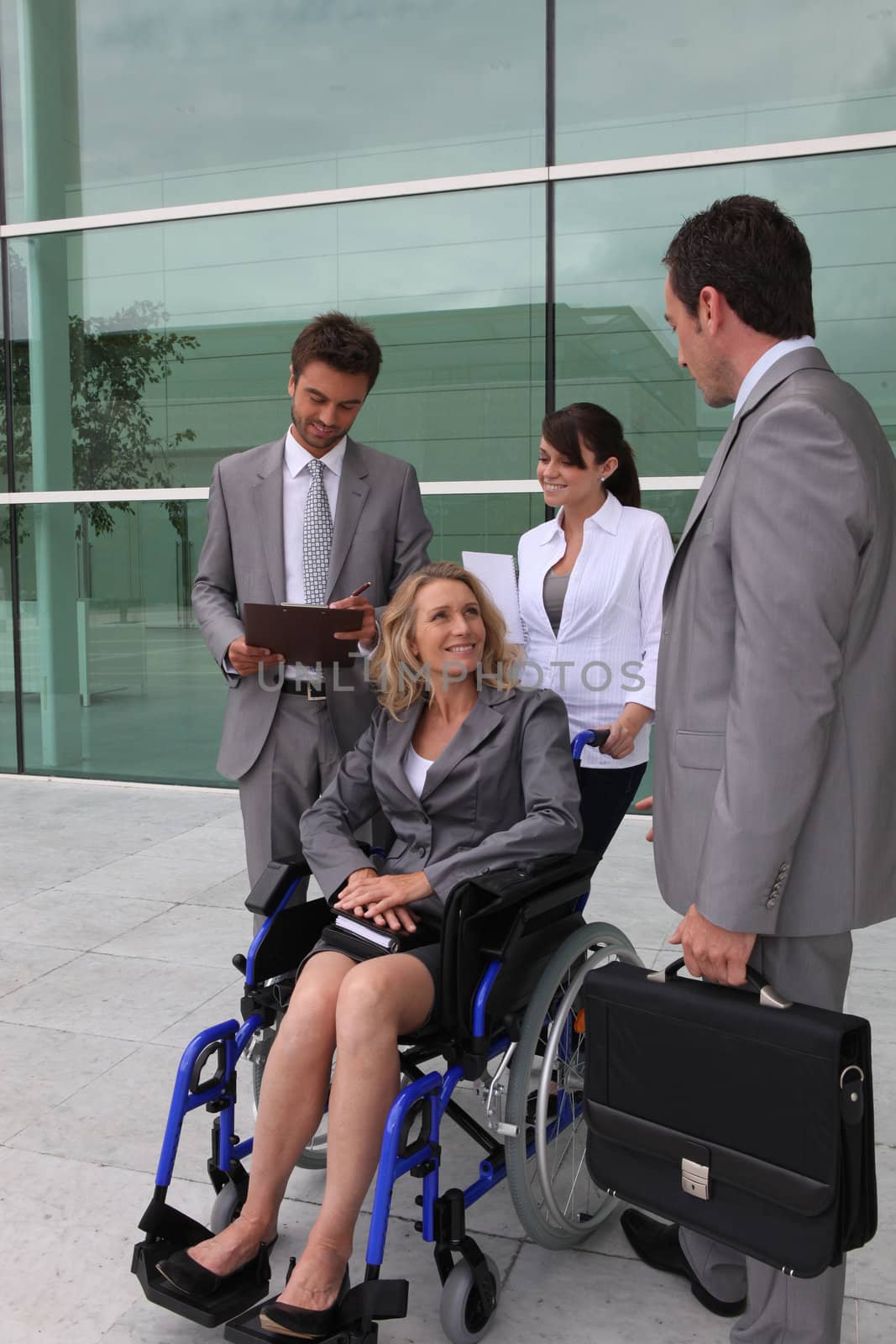 Businesswoman in a wheelchair with colleagues outside an office building