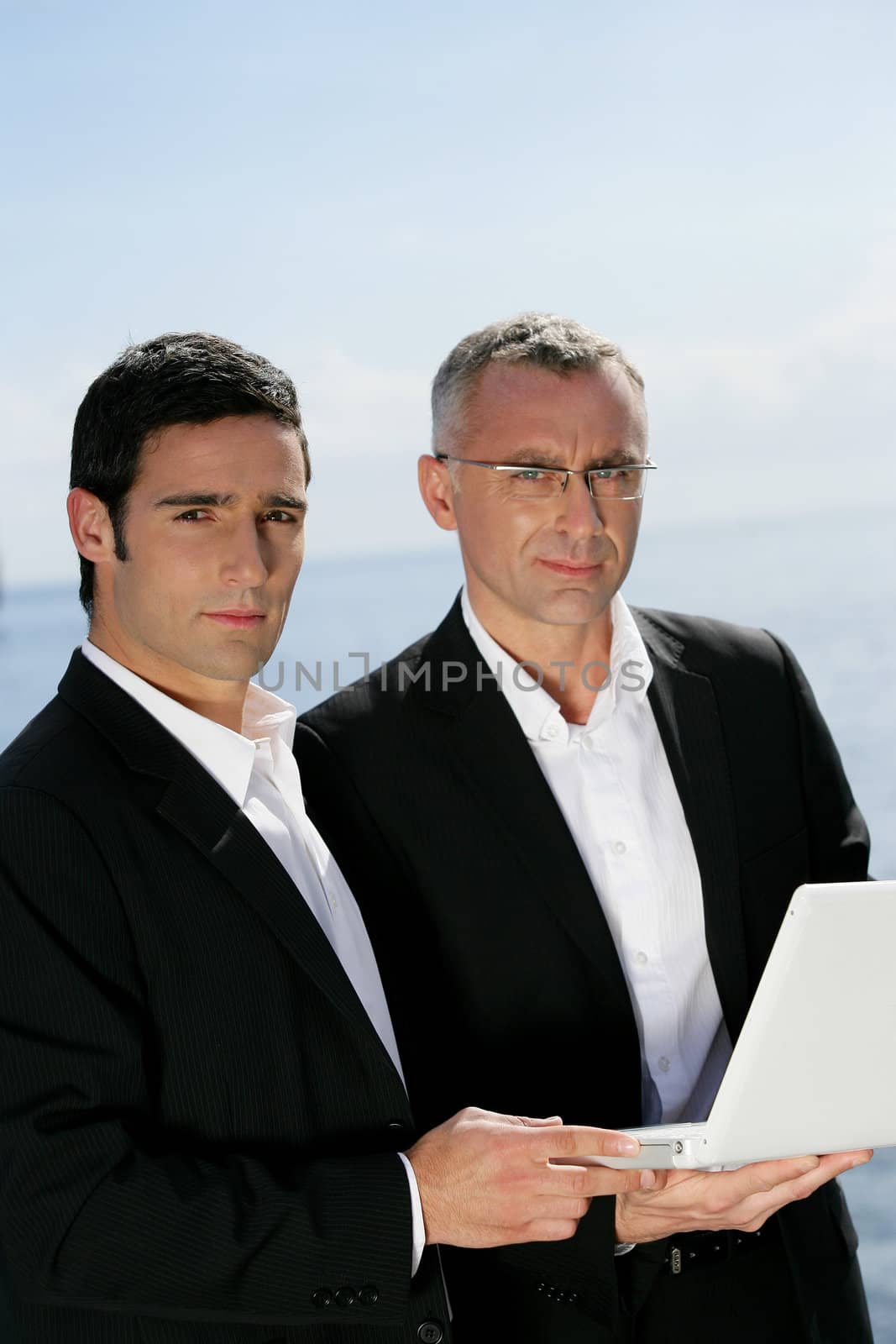 Two businessmen outdoors with laptop