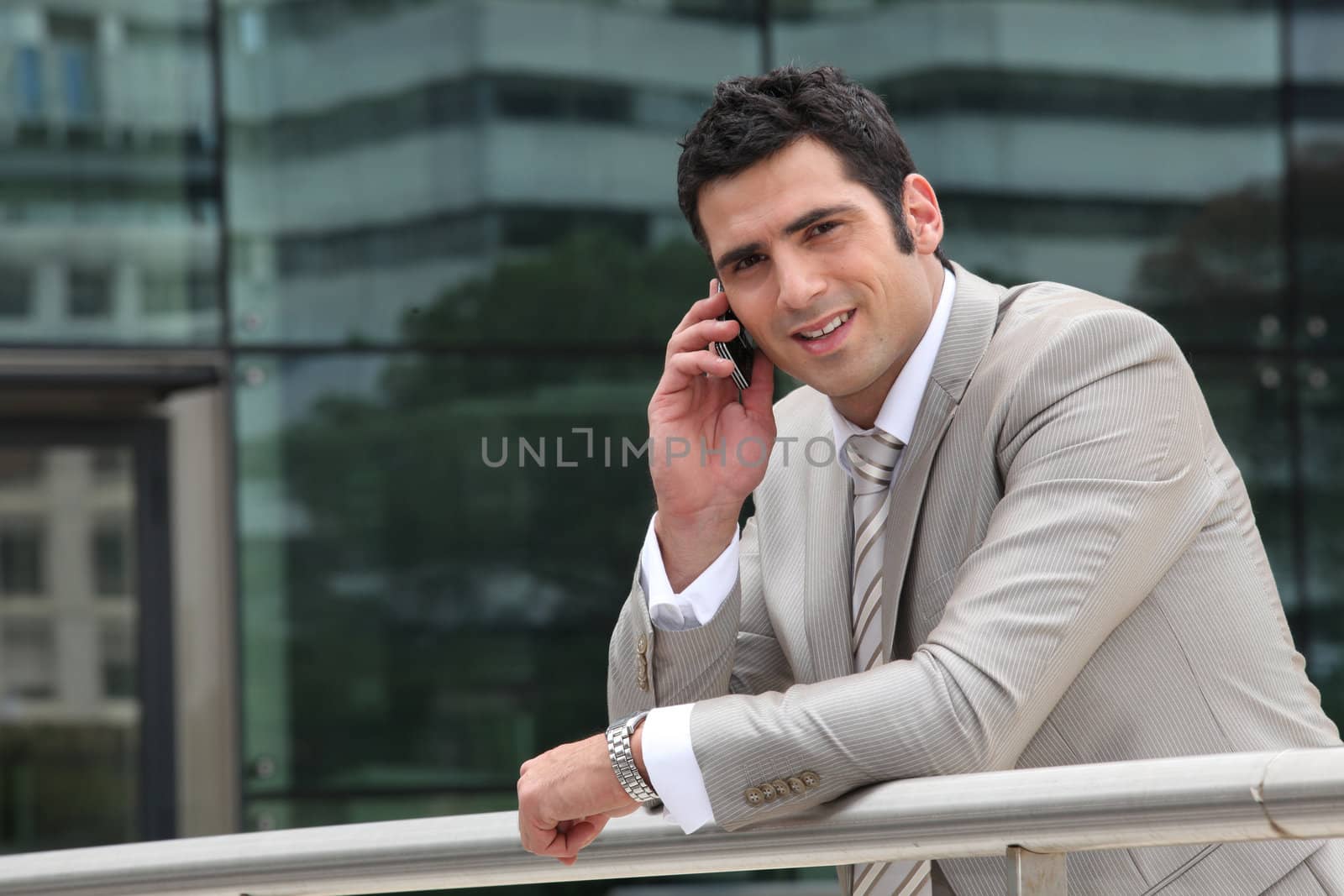 Man using a cellphone outside an office building by phovoir