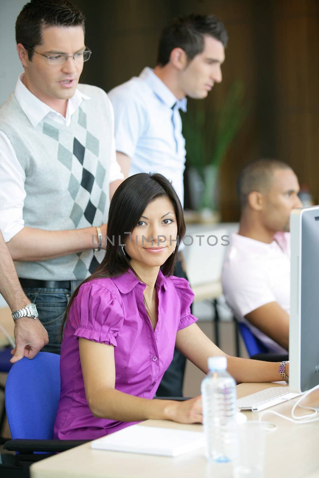 Woman working at a computer in a busy office by phovoir