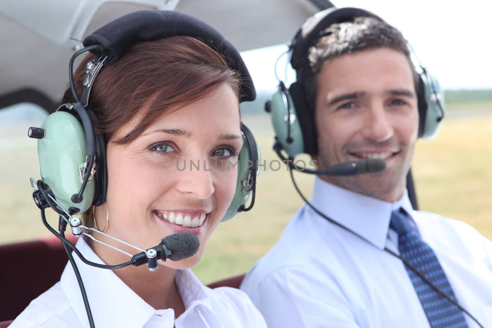 Man and woman wearing headsets in the open cockpit of a light aircraft