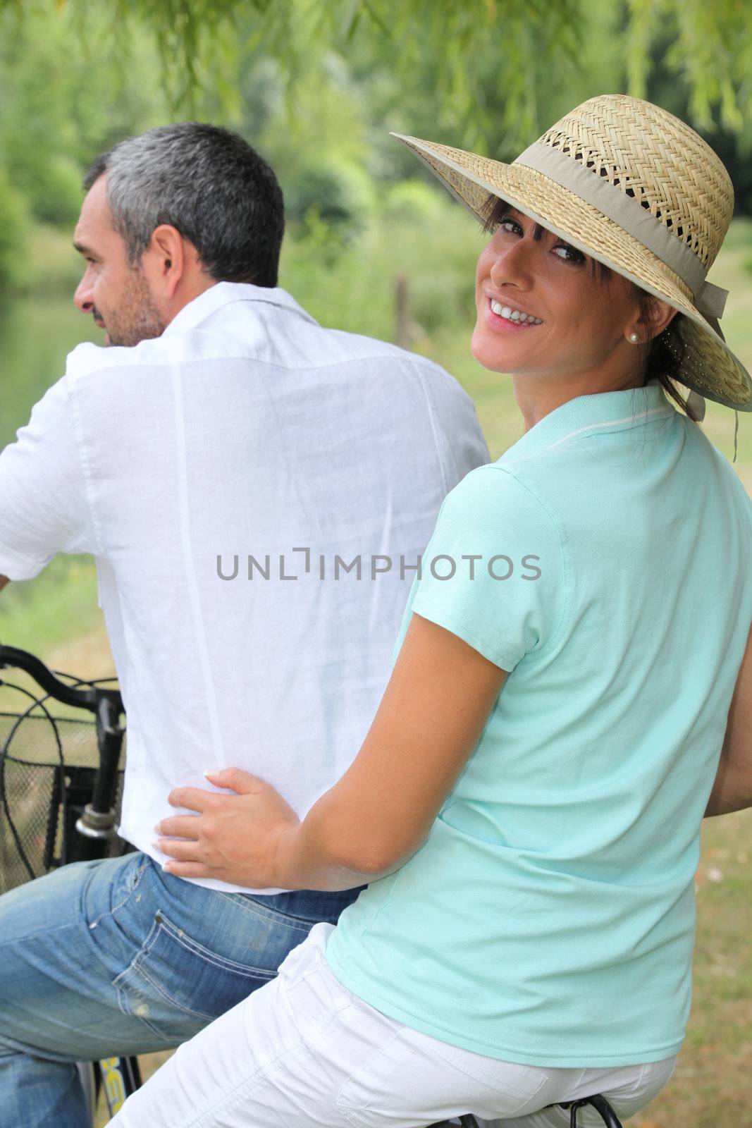 Couple riding on a bike together by phovoir