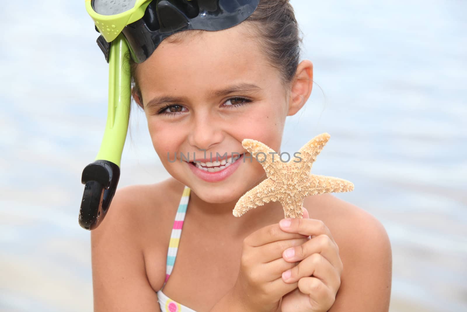 Little girl at the beach holding star fish by phovoir