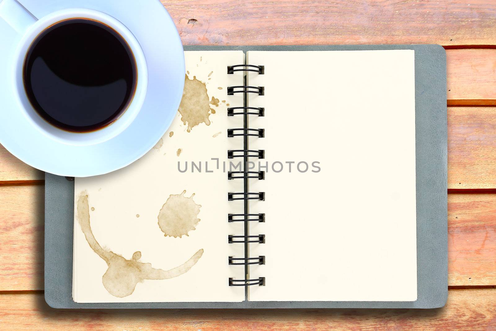 White cup of hot coffee and white sketch book on wood table