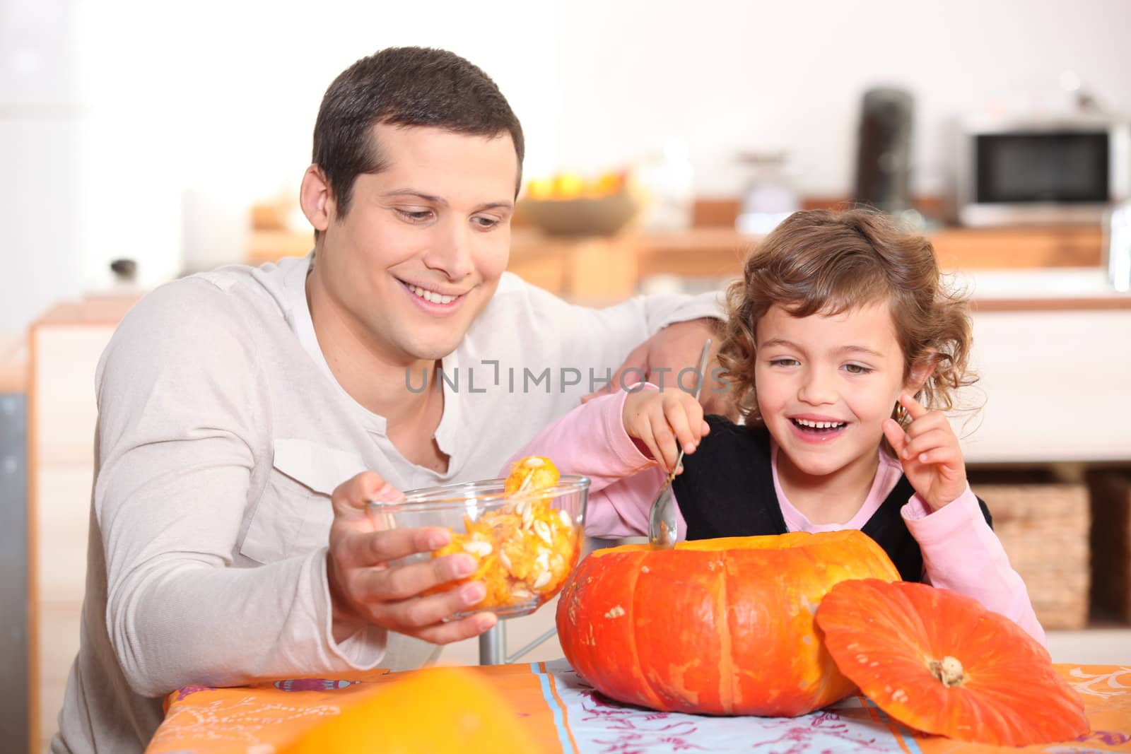 Girl preparing pumpkin with father