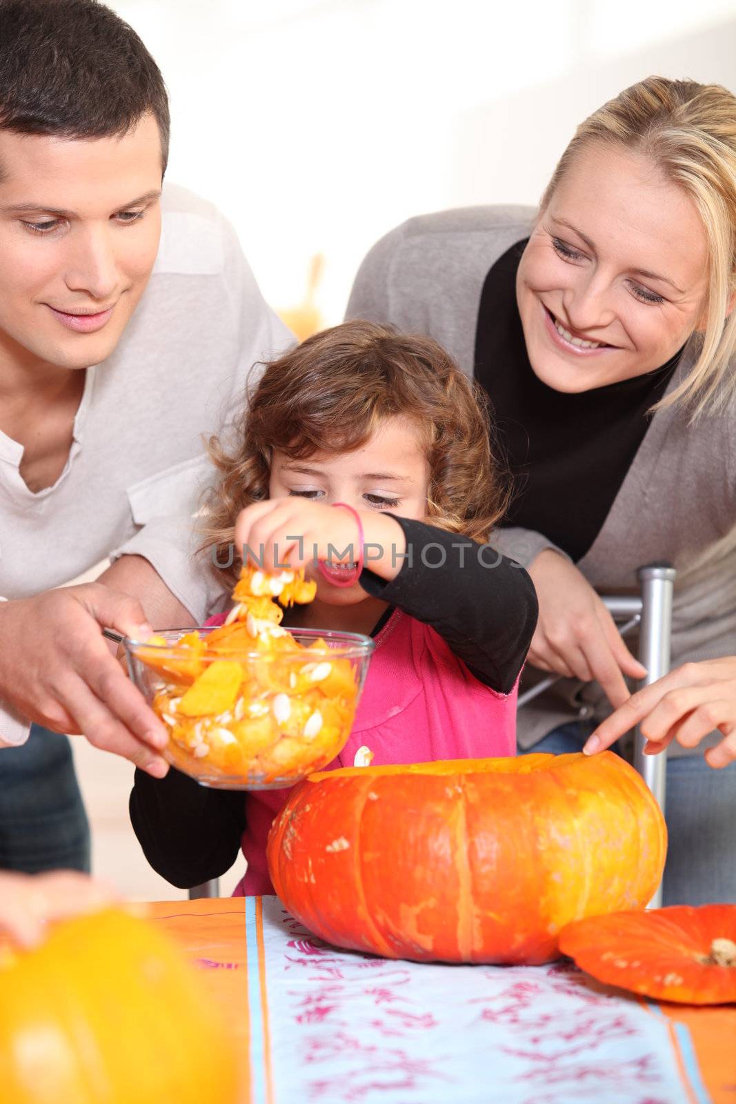 Young family carving hallowe'en pumpkins by phovoir