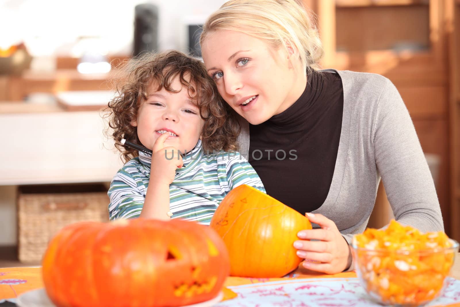 Mother and child carving pumpkins by phovoir