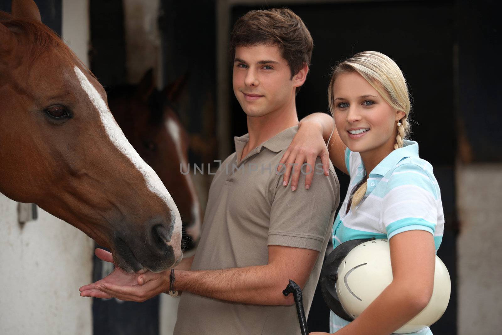 Young couple at a riding stable by phovoir