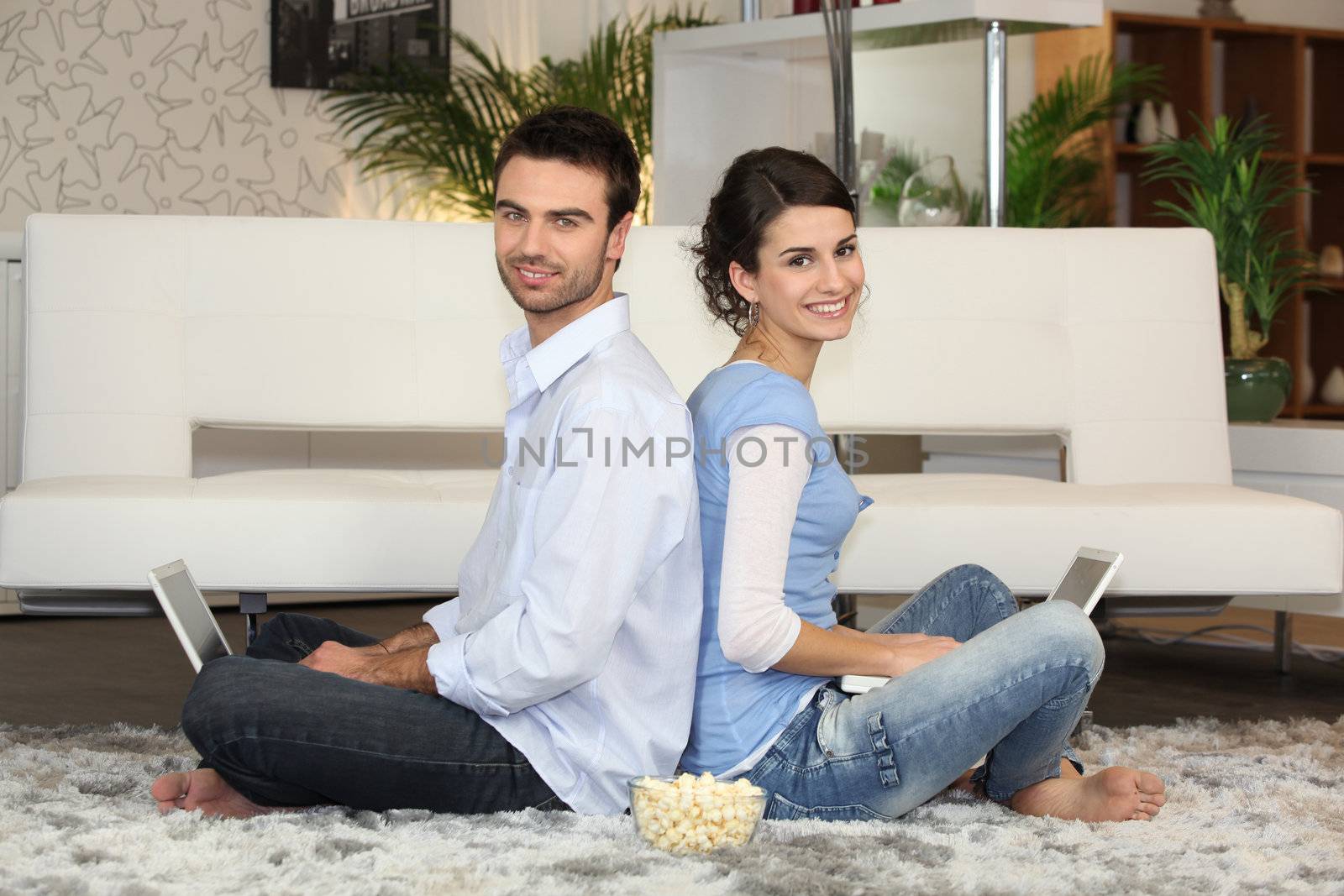 Couple sitting with laptop computers by phovoir
