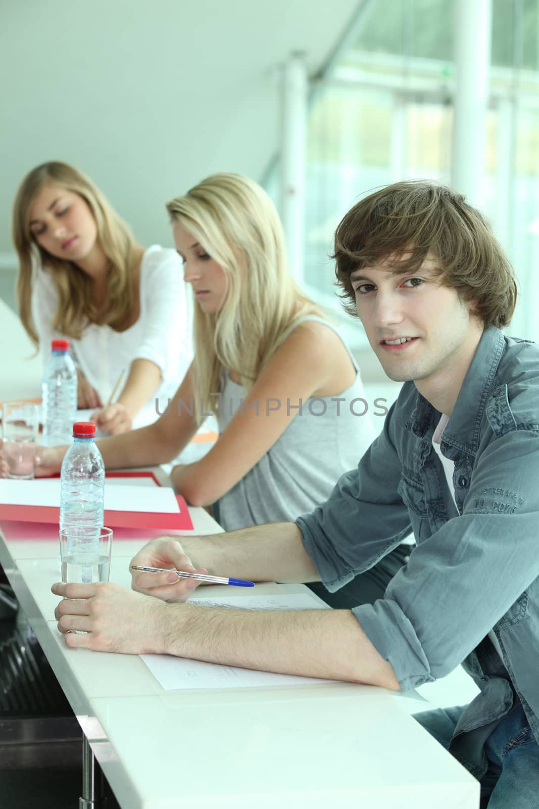 Young people in classroom by phovoir