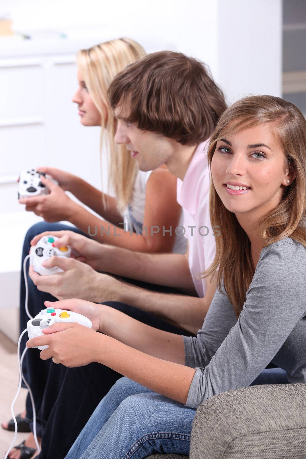 Three teenagers playing video games by phovoir