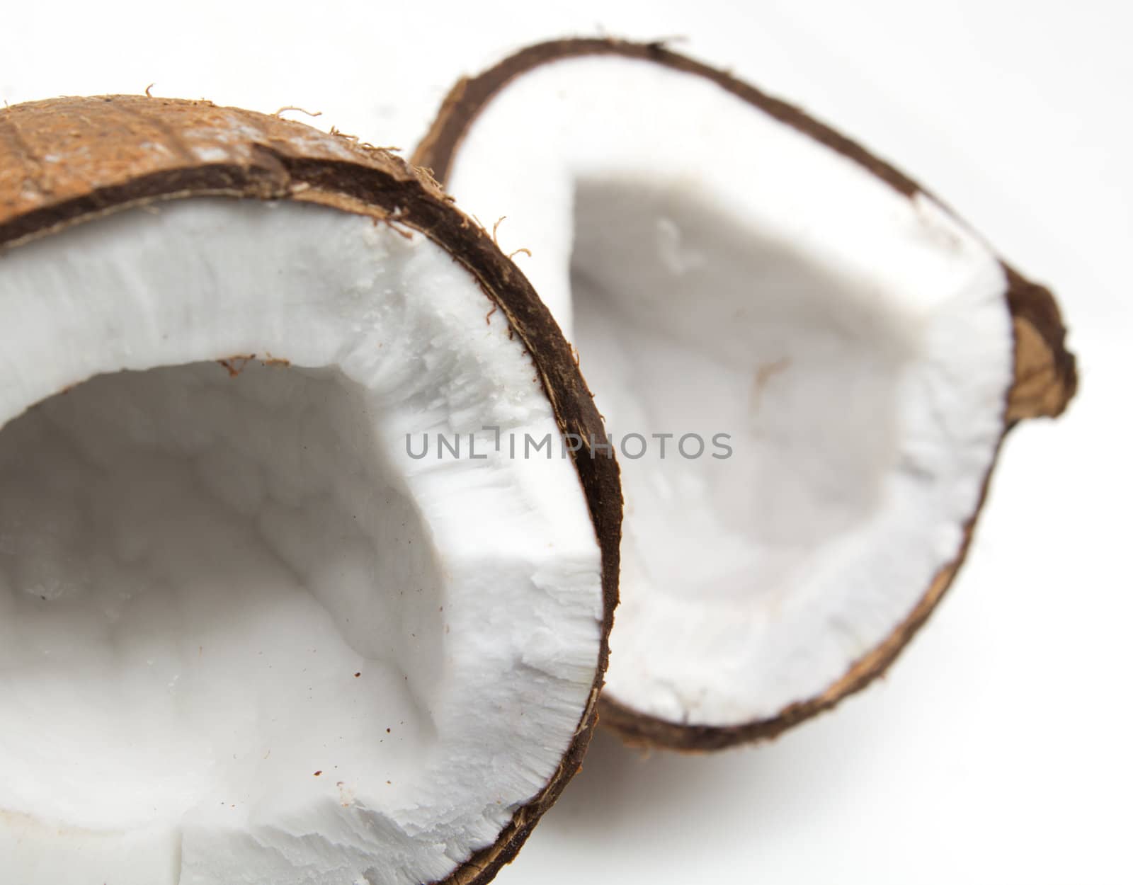 Closeup of cracked coconut on white background with light shadow. Shallow focus depth on front coconut 