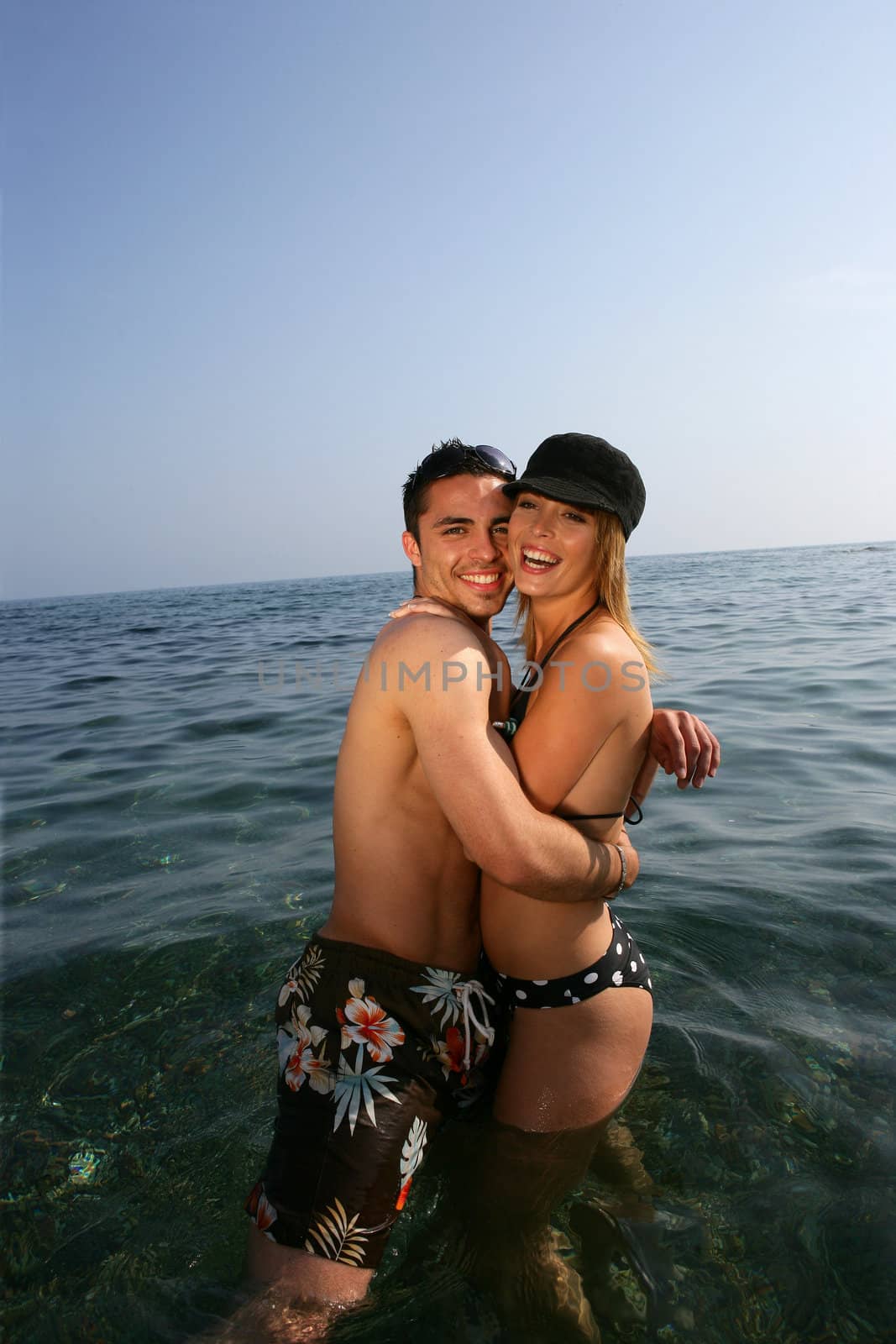Happy couple stood in the sea by phovoir