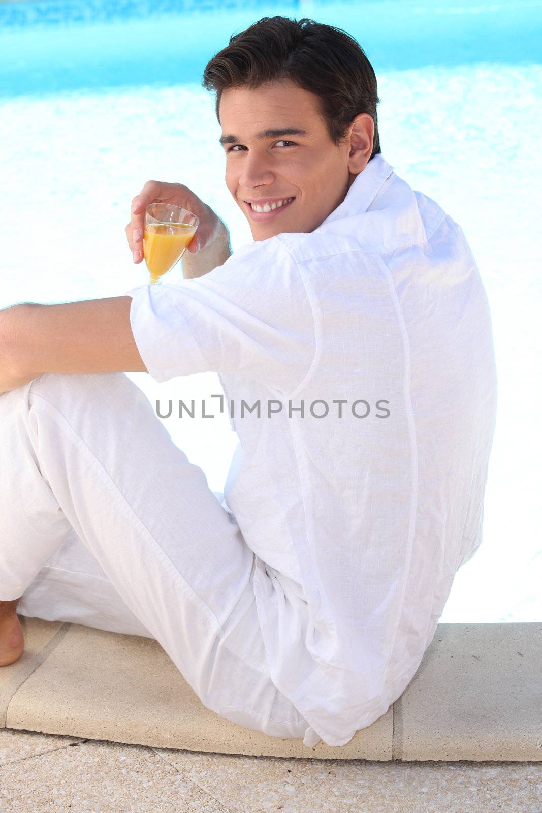 young man drinking cocktail on the beach by phovoir