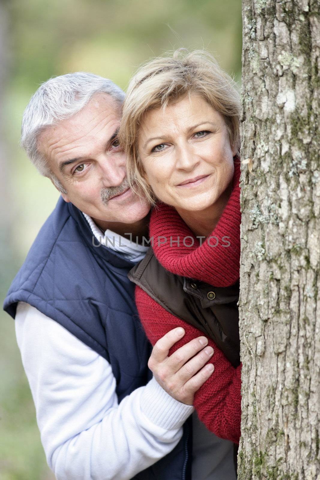 Older couple peeking around a tree