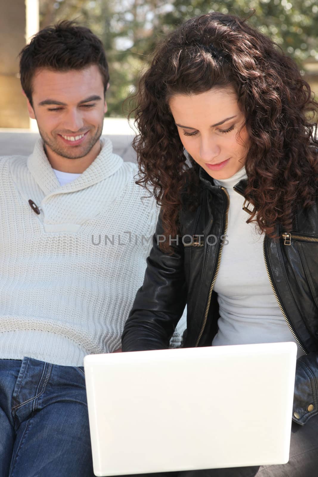Couple using a laptop outdoors