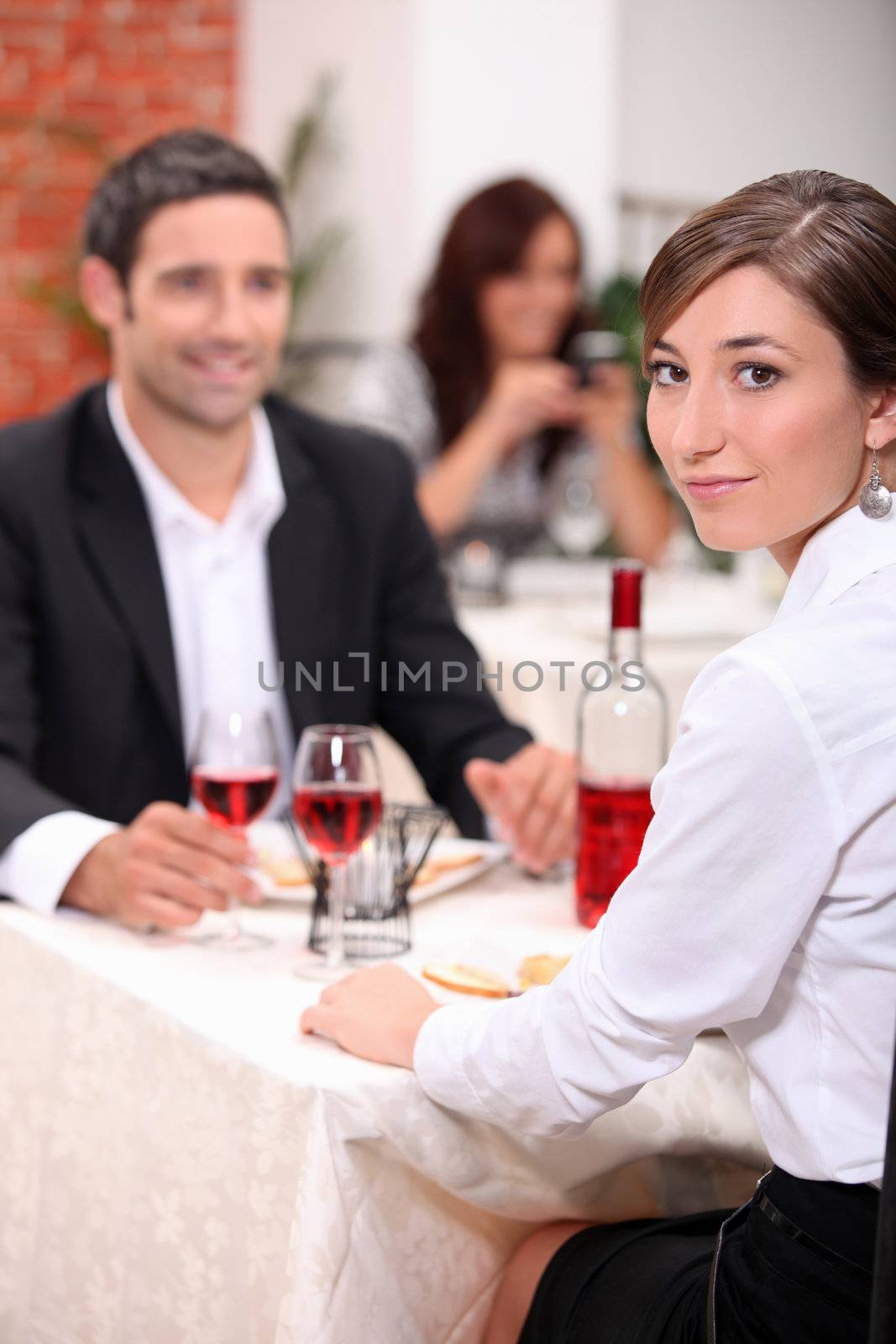 couple at restaurant with woman turned to camera by phovoir