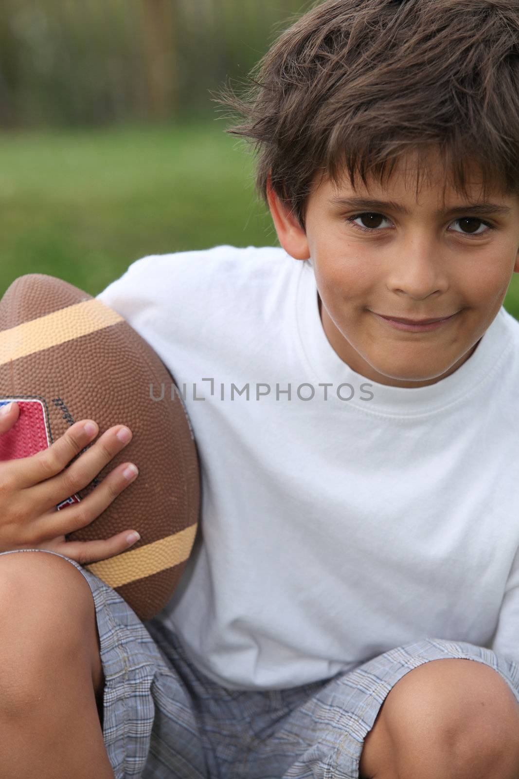 boy playing American football by phovoir
