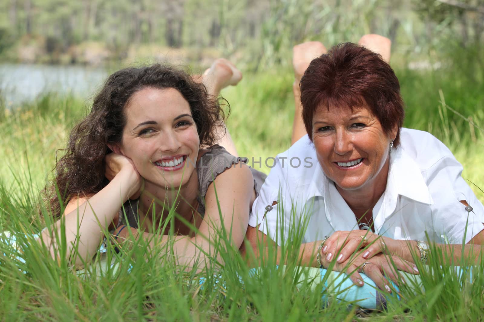 Older mother and adult daughter lying in the grass
