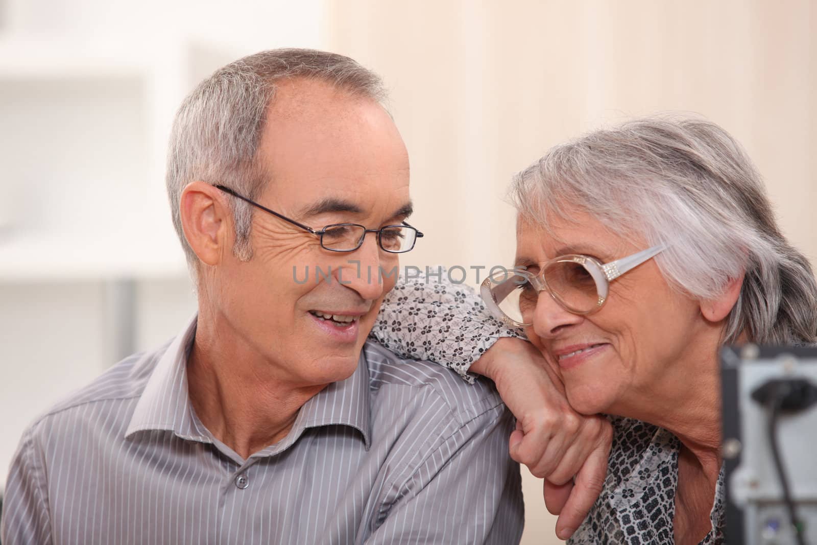 Smiling elderly couple at home by phovoir