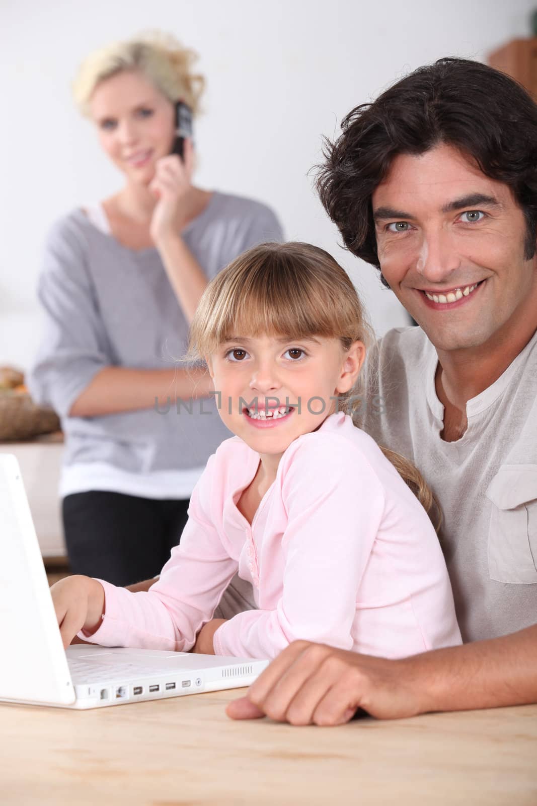 Dad and daughter using a laptop by phovoir