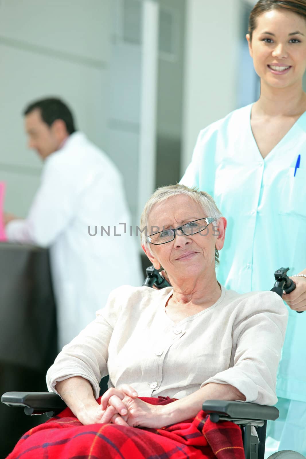Senior woman in wheelchair with young nurse by phovoir