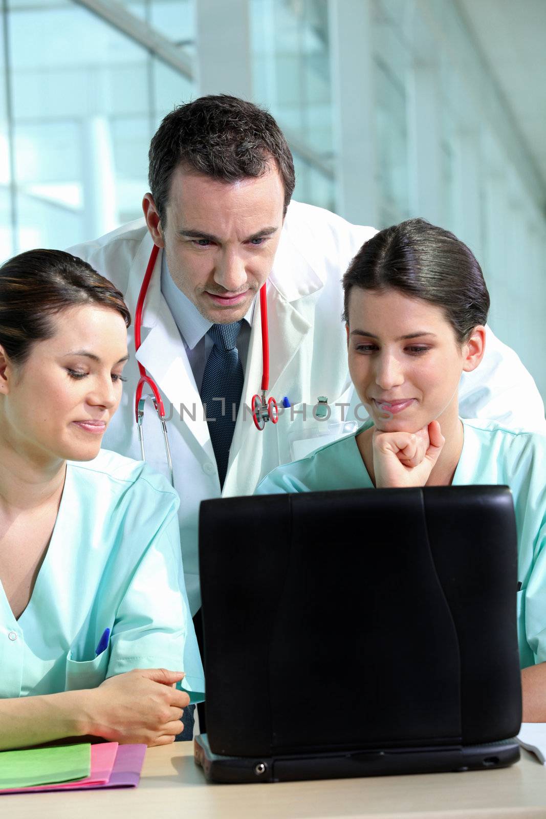 A team of medical professionals consulting patient records by phovoir