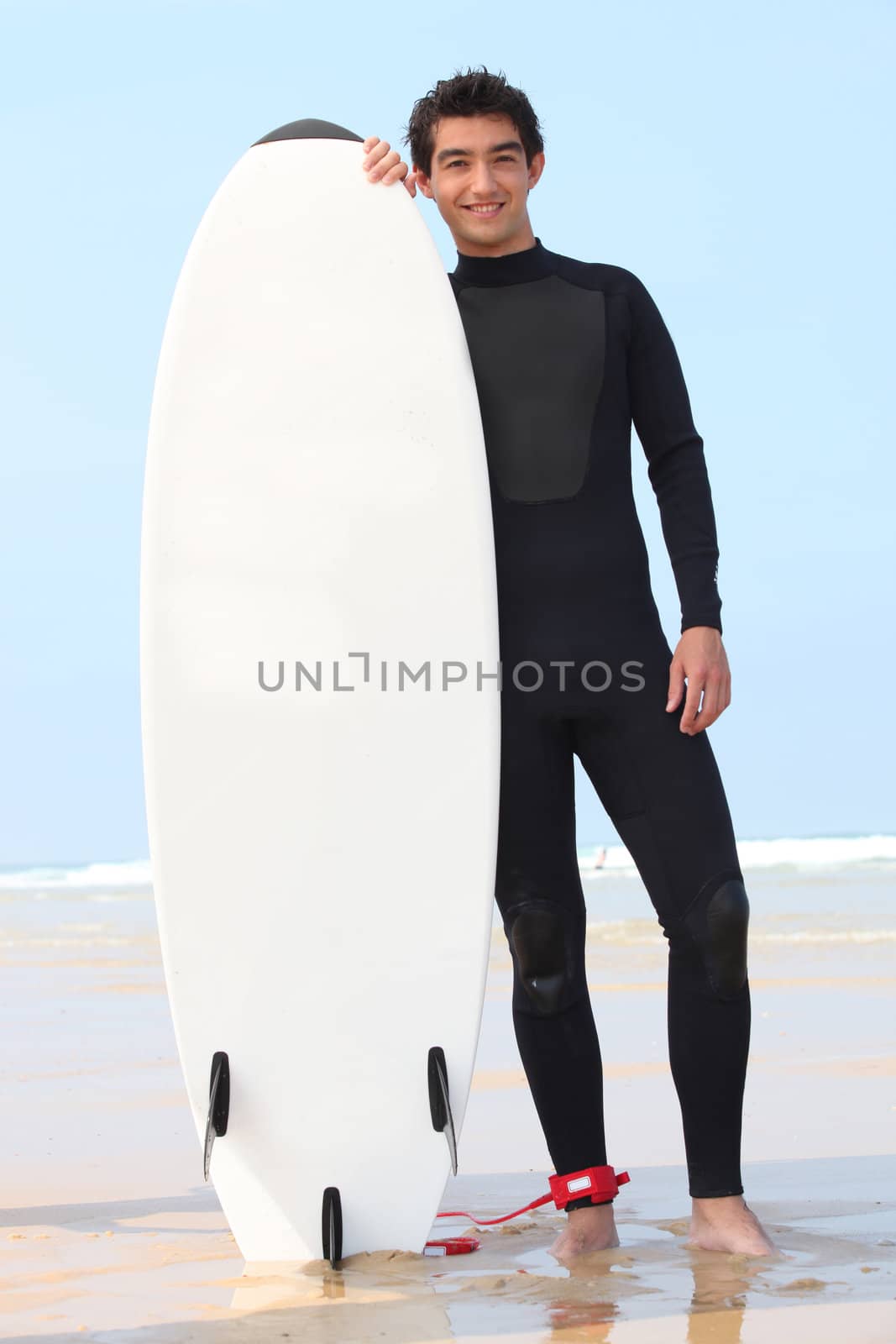 young surfer posing with board by phovoir