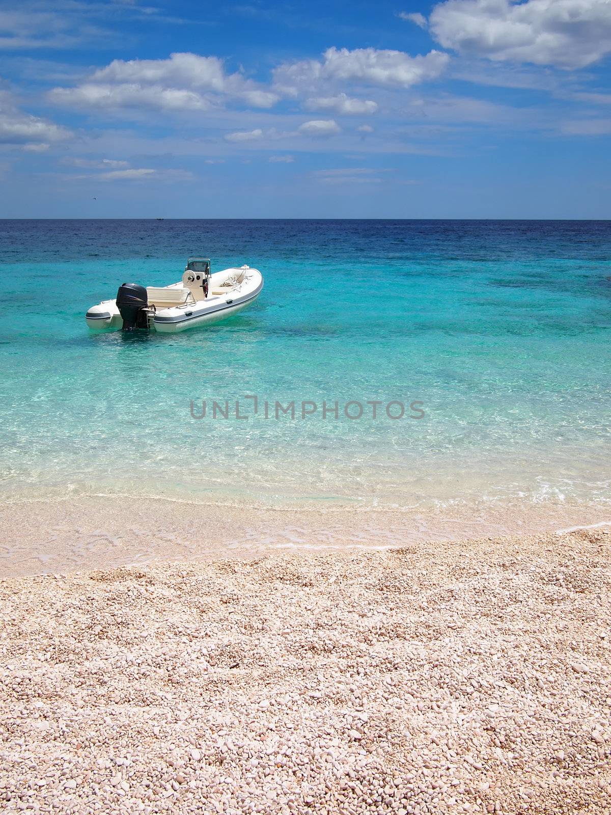Speedboat in an emerald sea in front of a private white sand beach on the east coast of Sardinia, Italy.