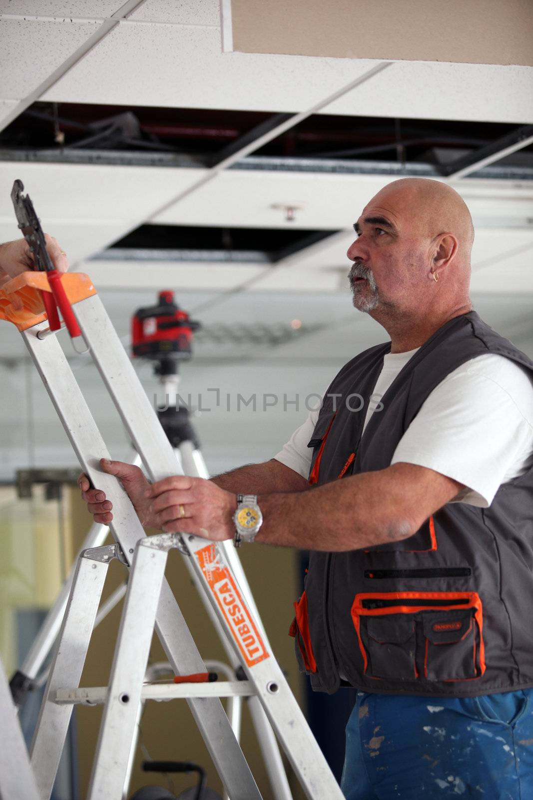 Building professional working on a suspended ceiling by phovoir
