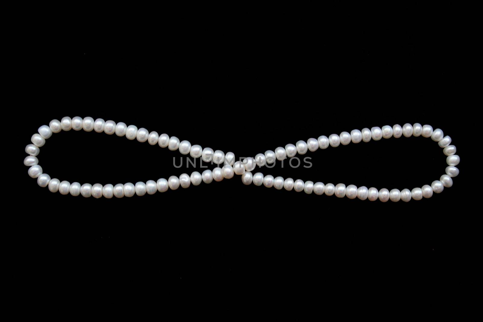 White pearls on the black silk as background 