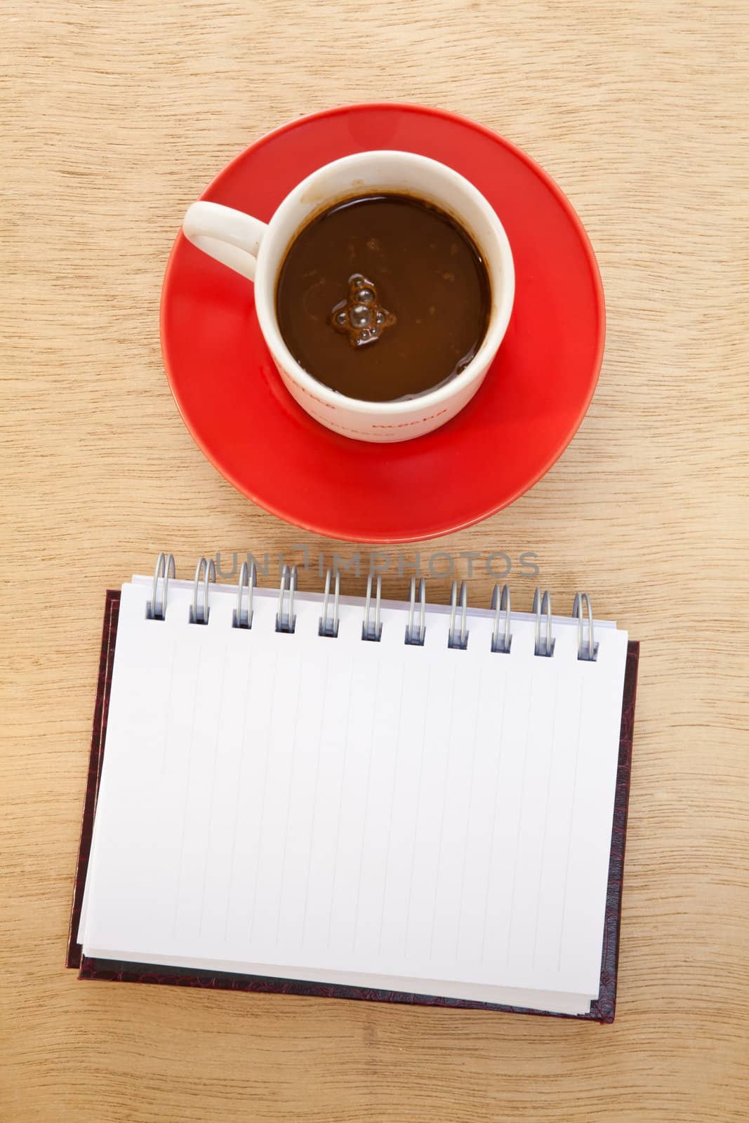 red cup of hot coffee and book on wood background