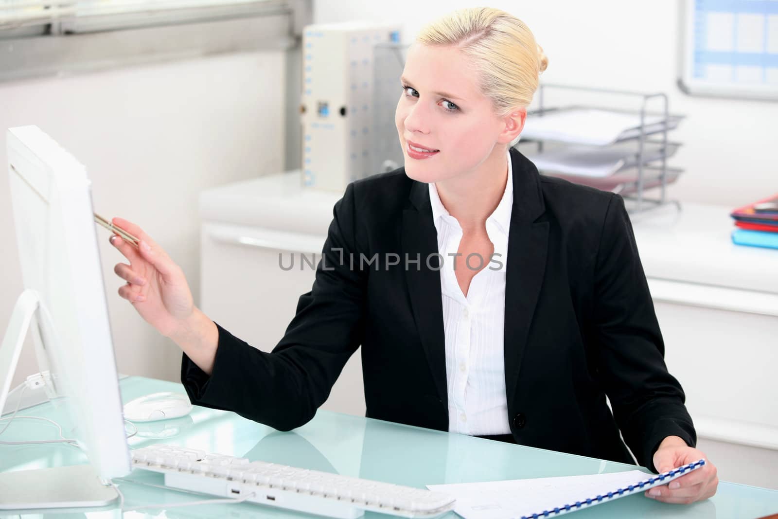 Blonde woman working at a clean modern desk by phovoir