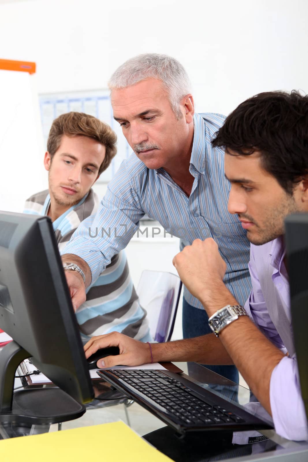 College lecturer showing students something on the computer by phovoir