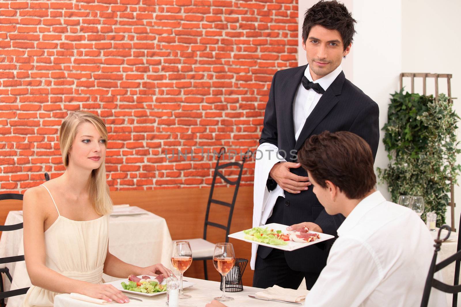 Waiter serving a young couple by phovoir