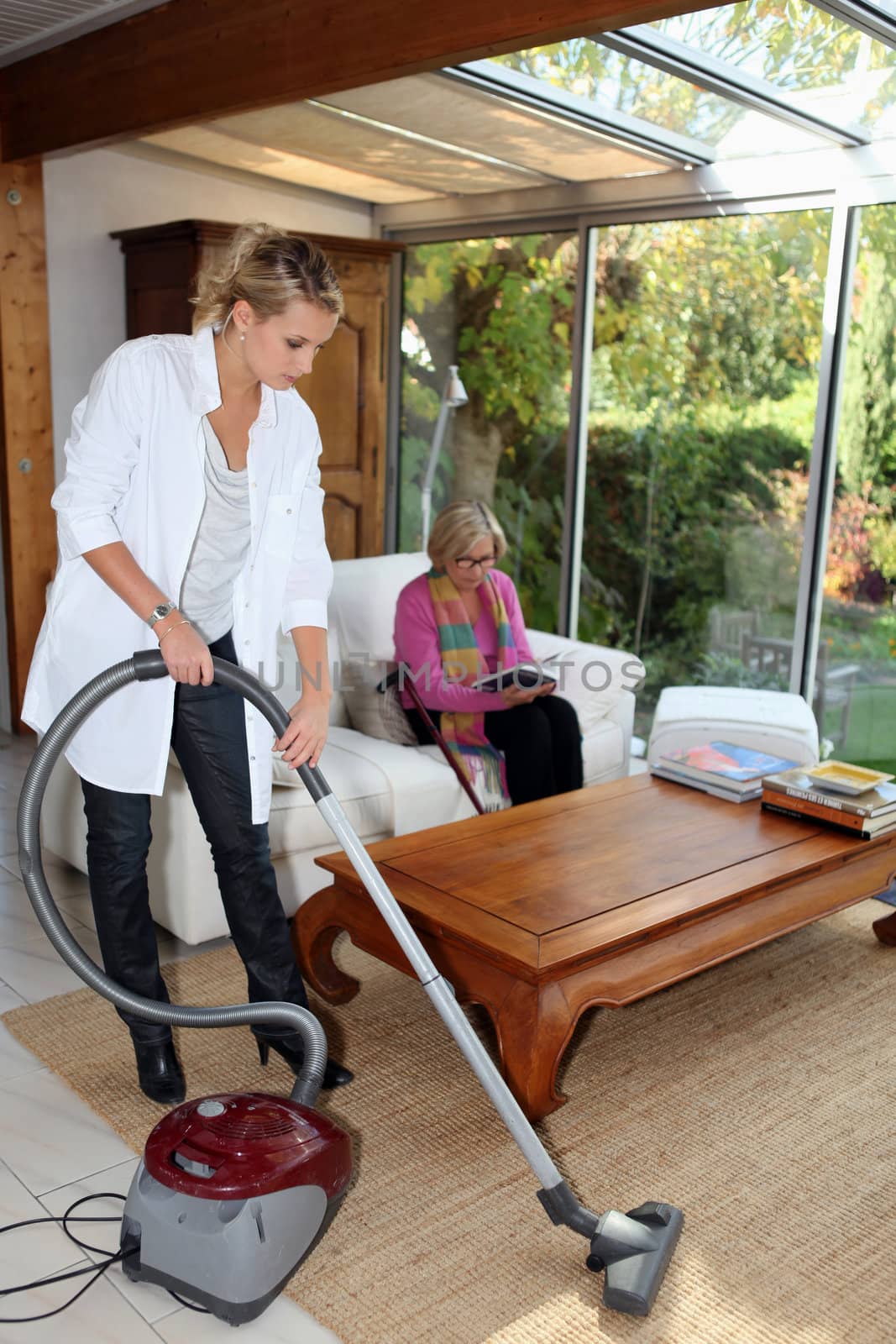 Girl vacuuming for an elderly woman by phovoir