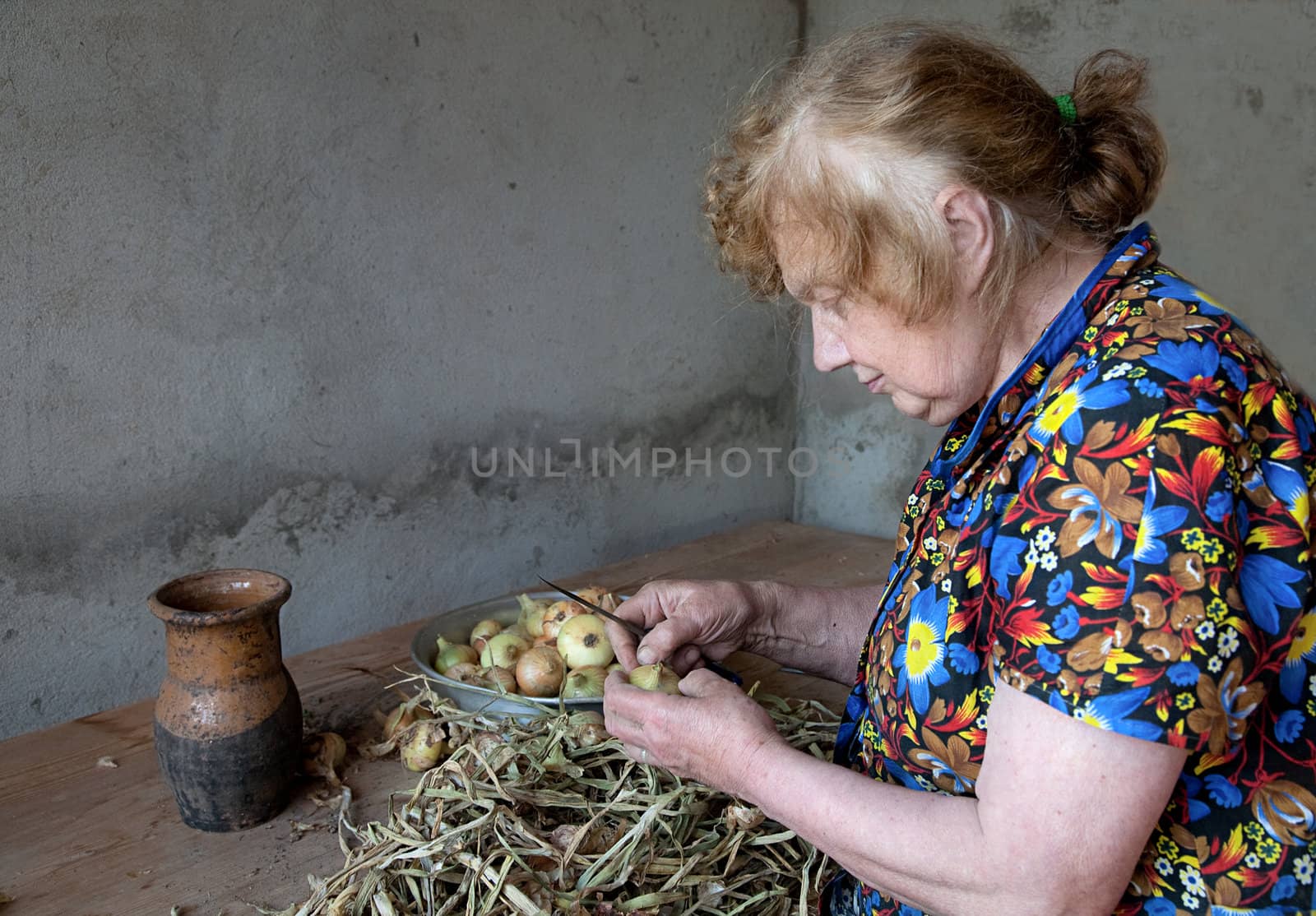 The old woman cuts an onions at itself in the house