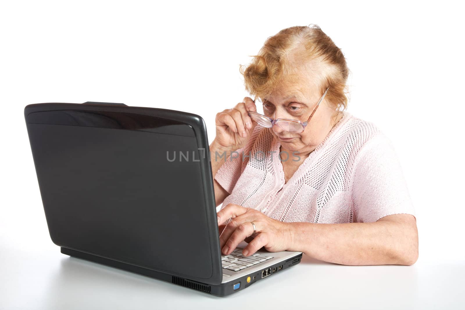 The old woman in glasses looks at the screen notebook on a white background
