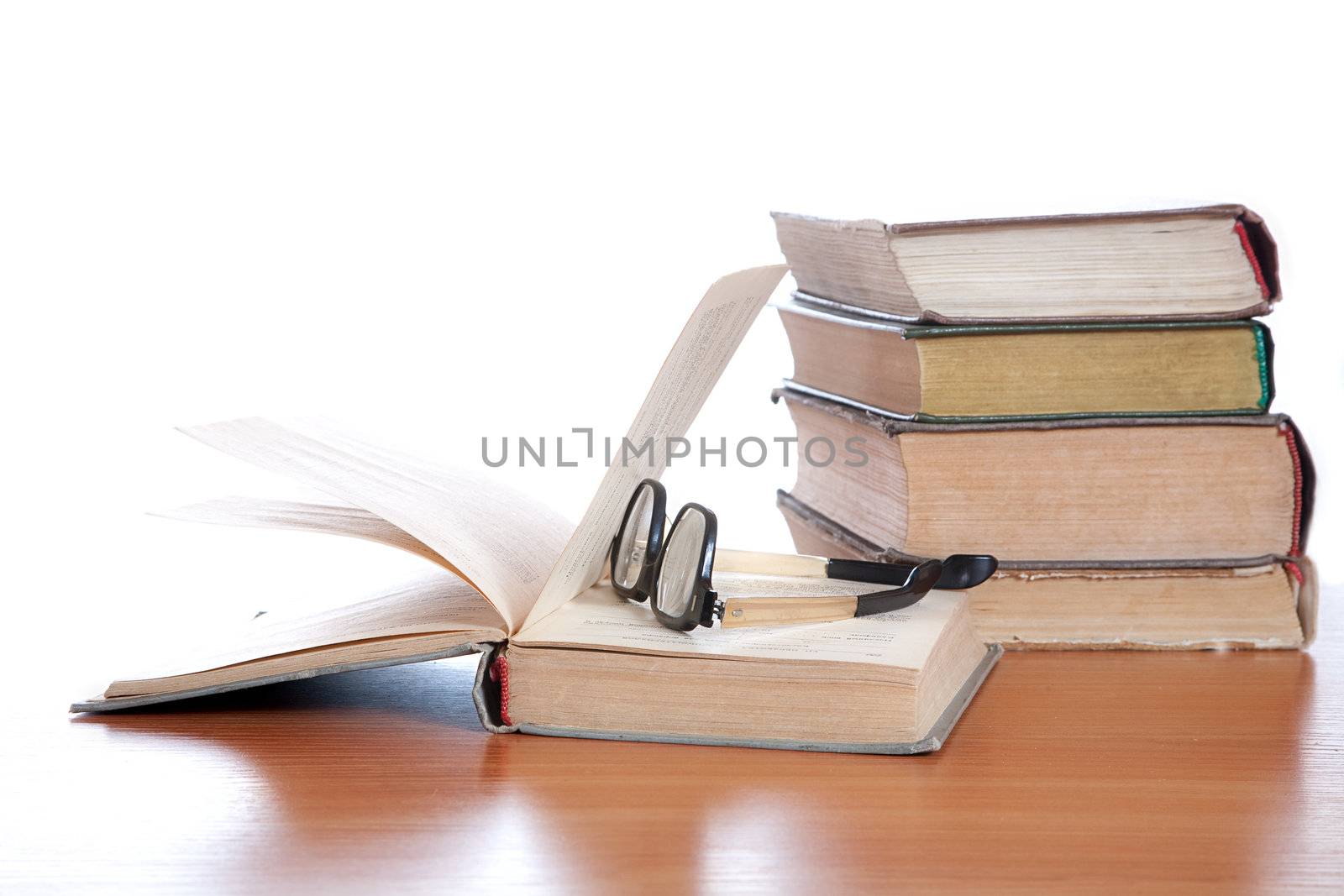 Old glasses and the old book on a white background