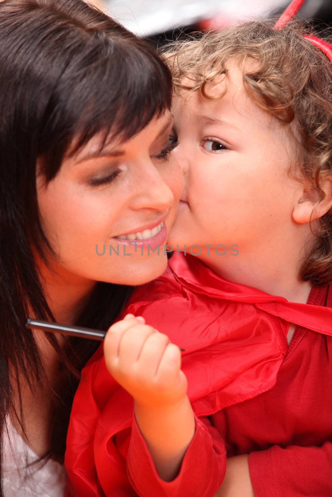 Child whispering into her mother's ear by phovoir