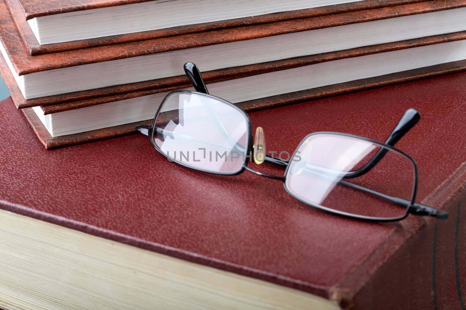 Pile of books and glasses on old thick volume