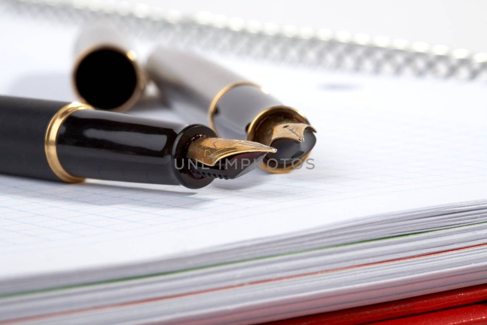 fountain pens lays on a writing-book with spiral