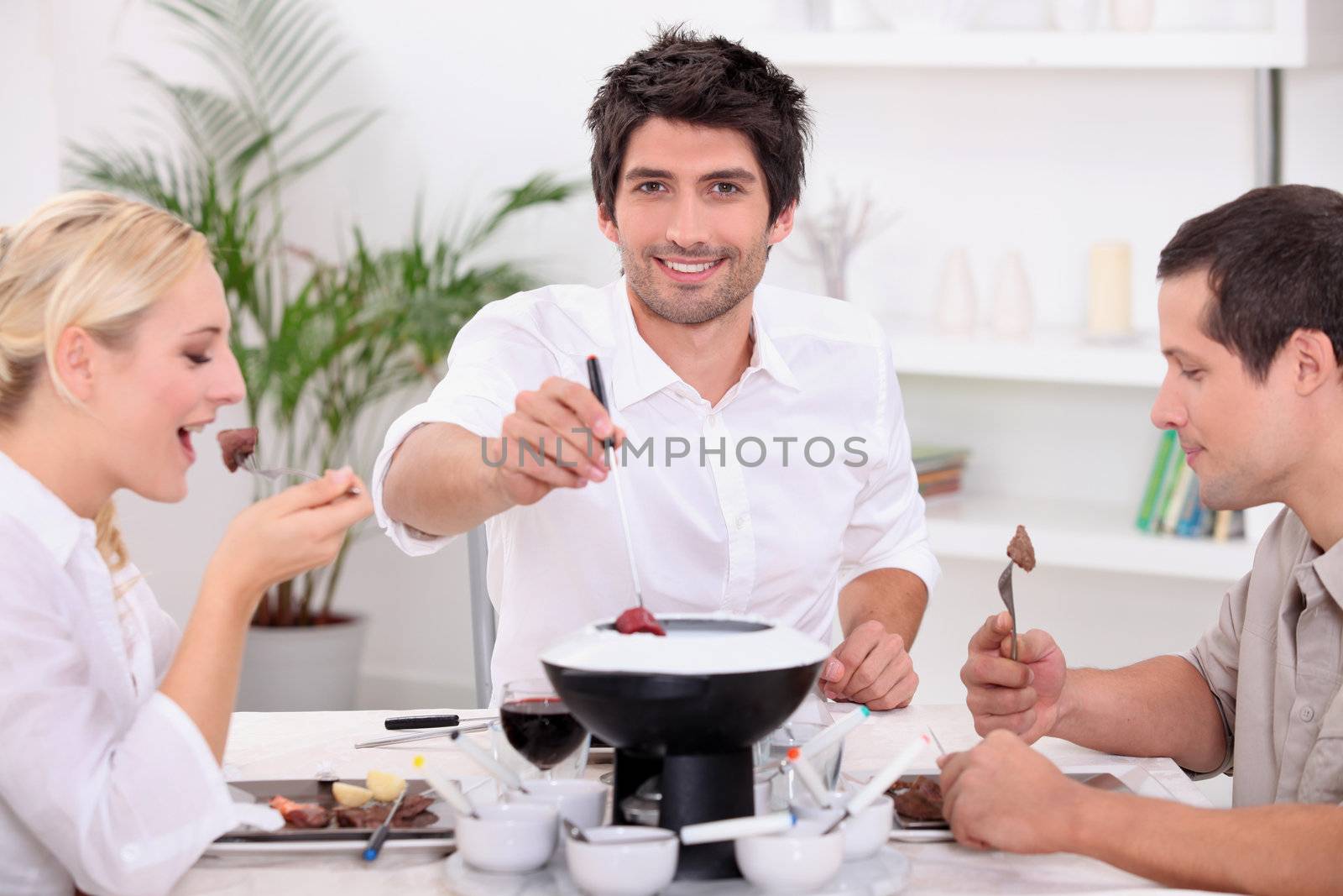 Friends enjoying chocolate fondue by phovoir